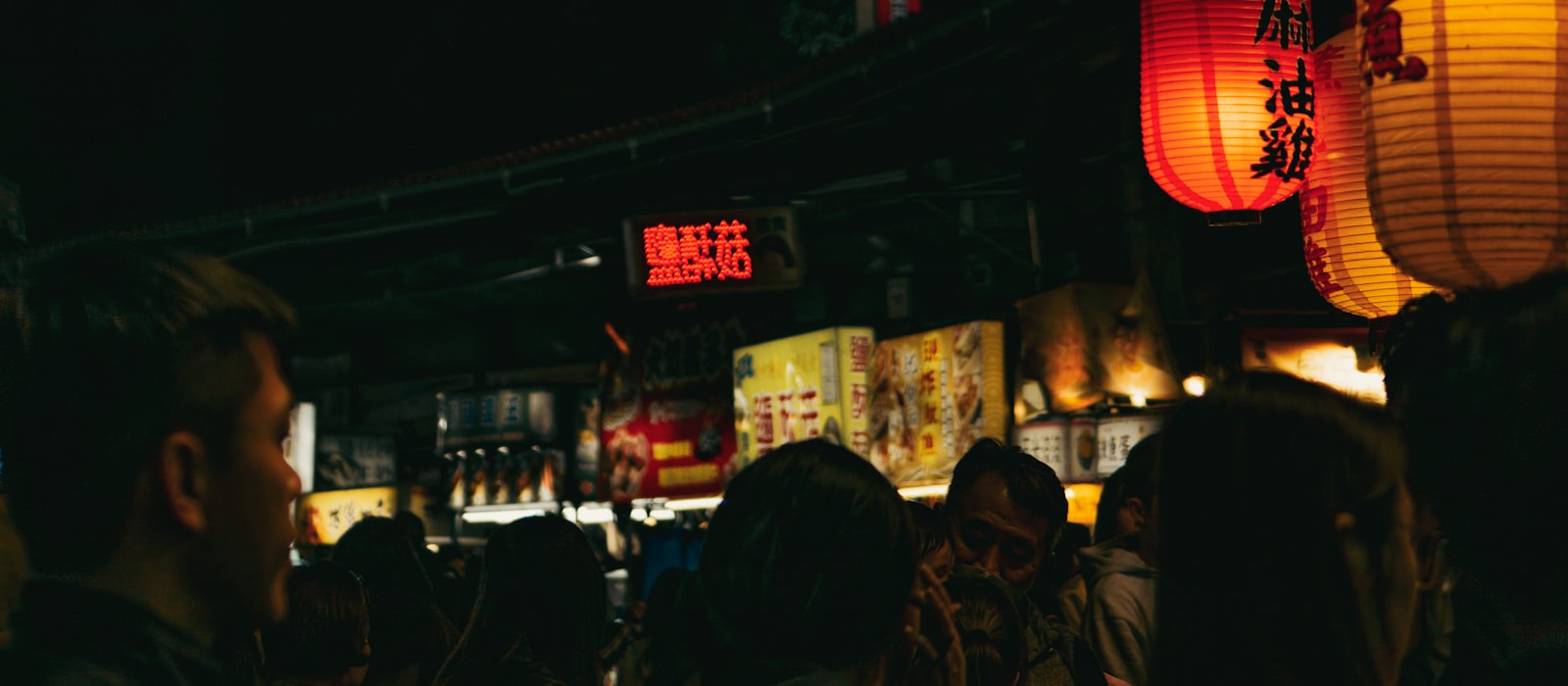 A night market glowing with lanterns and neon signs after dark